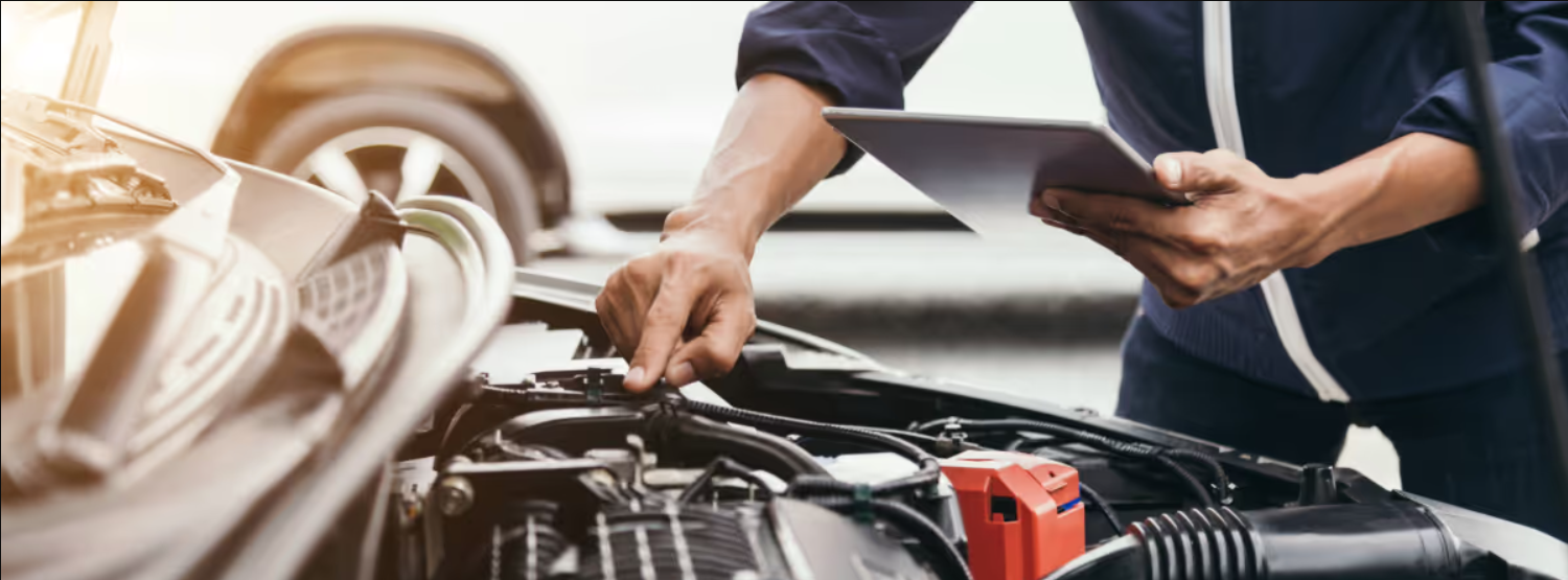 A zoomed in picture of a mechanic's hand working on a car engine